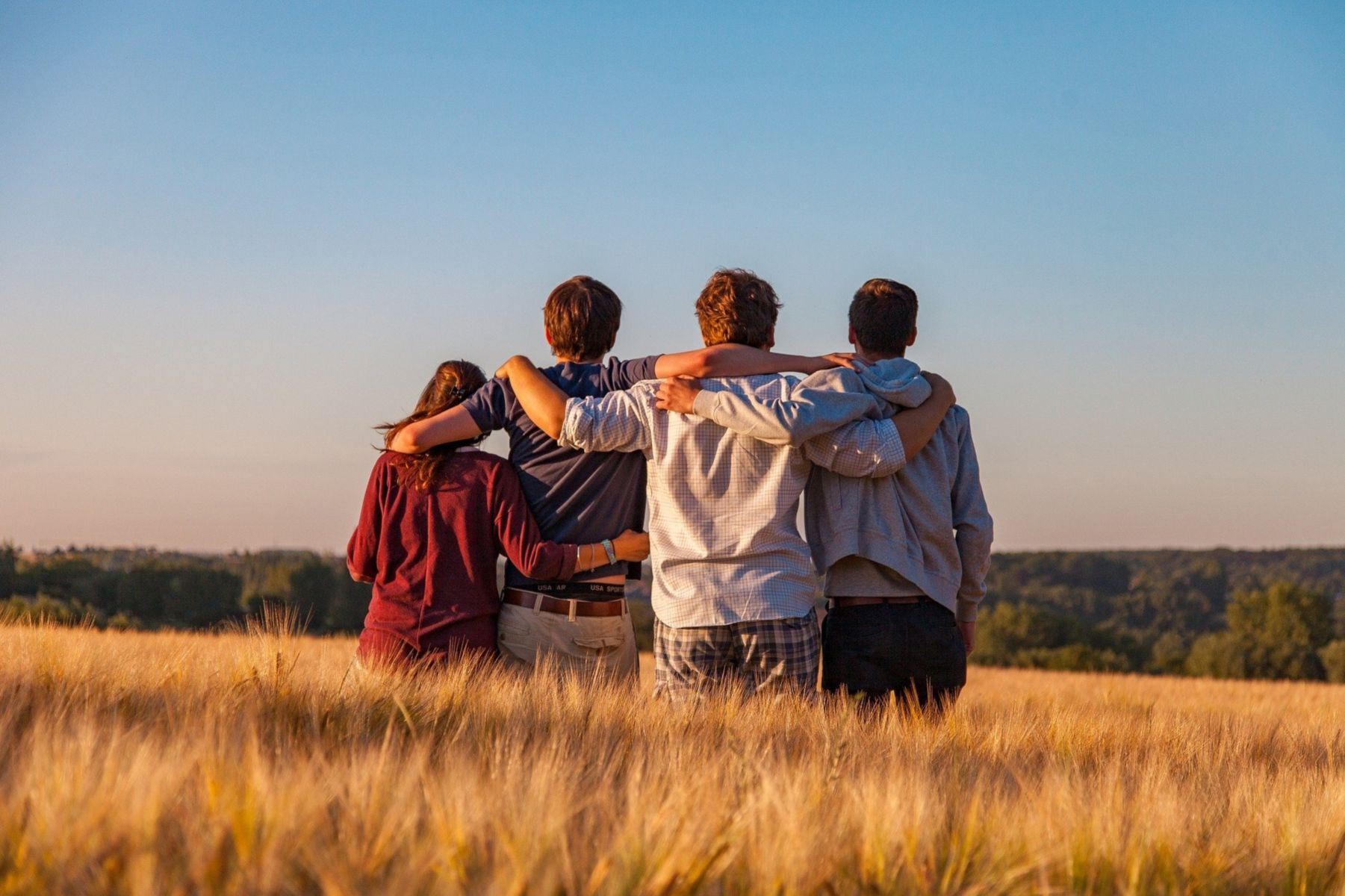 a group of teens in a field looking in the distance